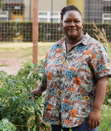 female smiling in a garden wearing a floral shirt